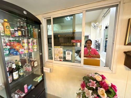 une femme derrière le comptoir d'un magasin d'alcools dans l'établissement นวนคร ออมสินอพาร์ตเมนต์ ติดห้างบิกซี Navanakorn Aomsin hotel near shopping mall,snooker and club, à Ban Lam Rua Taek