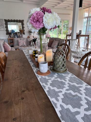 a dining room table with a vase of flowers and candles at Maryland Khaoyai Annapolis Pool Villa in Ban Nong Song Hong