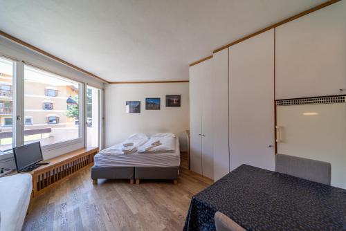a bedroom with a bed and a desk and a window at Chesa Pradatsch Suot - Celerina in Celerina