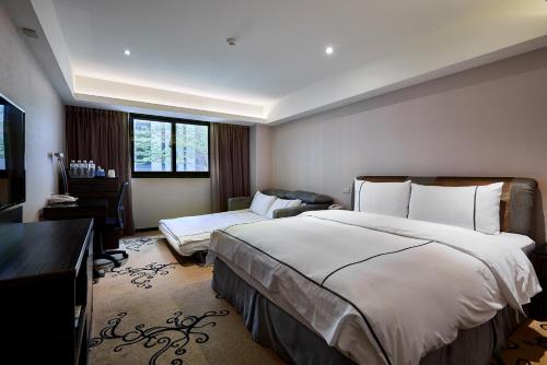 a hotel room with a large bed and a desk at K Hotel Taipei in Taipei