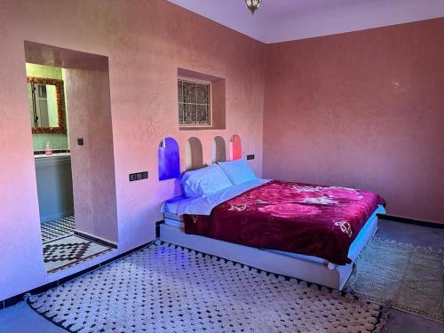 1 dormitorio con 1 cama en una pared de color rosa en Gîte d'étape Tamaloute, en Bou Drarar