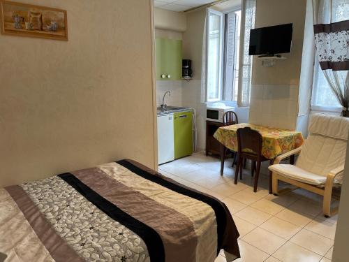 ein Schlafzimmer mit einem Bett und einem Tisch sowie eine Küche in der Unterkunft Aquanerius Résidence in Néris-les-Bains