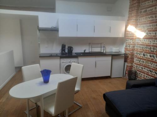 uma pequena cozinha com uma mesa branca e cadeiras em Appartement de charme Toulouse nord em Aucamville