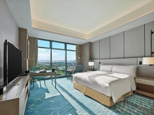 a bedroom with a bed and a desk and a television at Hilton Beijing Tongzhou in Beijing