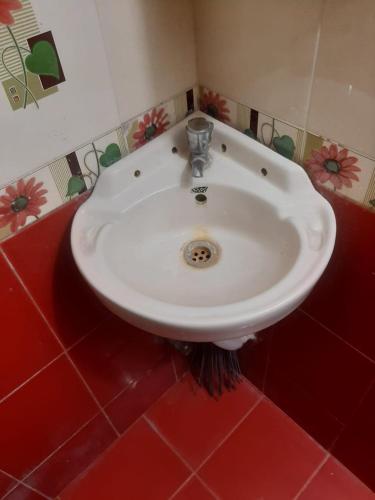 a white sink in a bathroom with red tiles at Darsh Bungalow....Amol Pade in Neral