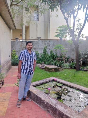a man standing next to a pond in a garden at Darsh Bungalow....Amol Pade in Neral