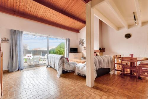 un salon avec une table et une grande fenêtre dans l'établissement Bretignolles-sur-mer - 450m de la plage, à Bretignolles-sur-Mer