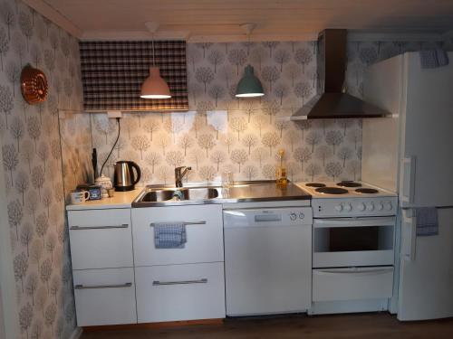 a white kitchen with a sink and a stove at Kalix Riverside inn, Farm timbering in Kalix