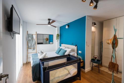 1 dormitorio con cama y pared azul en Casa El Palo, en Málaga