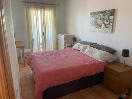 a bedroom with a bed with a pink comforter at Encantador piso con vistas al mar in Puerto de Mazarrón