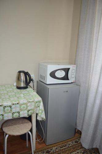 a microwave sitting on top of a refrigerator next to a table at Apartment on 5 microdistrict, 8 in Bishkek
