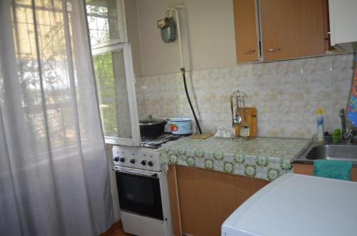 a kitchen with a stove and a sink and a window at Apartment on 5 microdistrict, 8 in Bishkek