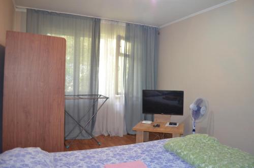 a bedroom with a bed and a tv and a window at Apartment on 5 microdistrict, 8 in Bishkek