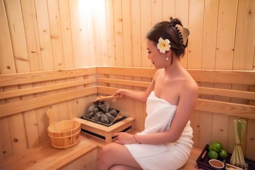 a woman sitting in a sauna at Canvas Danang Beach Hotel in Da Nang