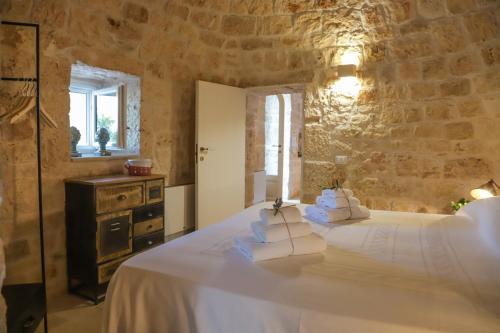 - une chambre avec un lit et un mur en pierre dans l'établissement Trulli Dimore - Trulli Balice, à Antonelli