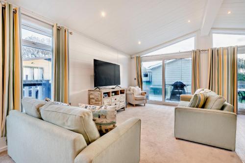 a living room with two couches and a flat screen tv at Belvedere Lodge, Shorefield Country Park, Shorefield Rd, Milford on Sea, Lymington SO41 0LH in Lymington