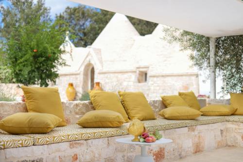 a couch with yellow pillows on a patio at TD Trulli Balice Cozy Trulli with Pool in Antonelli