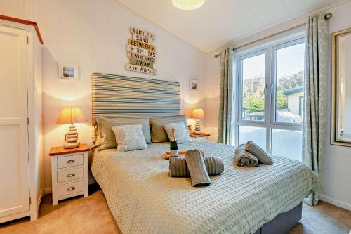 a bedroom with a bed and a large window at Belvedere Lodge, Shorefield Country Park, Shorefield Rd, Milford on Sea, Lymington SO41 0LH in Lymington