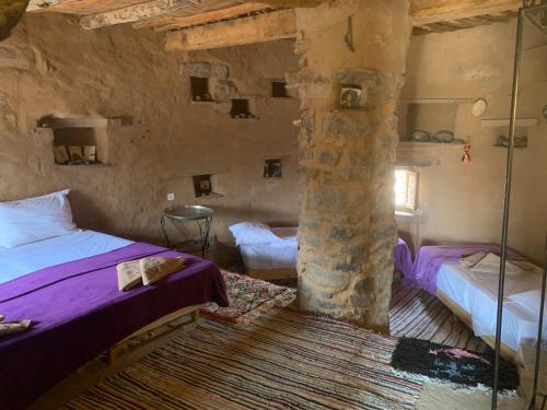 a bedroom with two beds and a stone pillar at Maison Boutchrafine in Erfoud