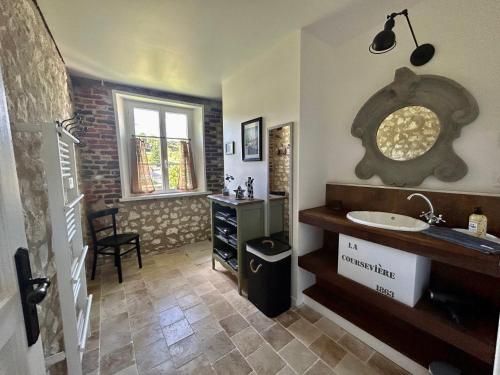 La salle de bains est pourvue d'un lavabo et d'un comptoir avec un miroir. dans l'établissement Gîte de la Coursevière - Proximité des plages de la Côte d Opale, Nausicaá et Montreuil-Sur-Mer, à Doudeauville