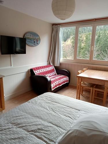 a bedroom with a bed and a chair and a window at Résidence LE BEC DE L'AIGLE in Le Lioran