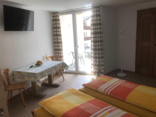Zimmer mit 2 Betten, einem Tisch und einem Fenster in der Unterkunft B&B Alpina in Le Prese