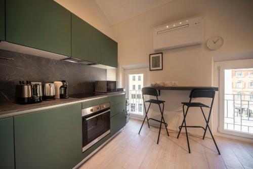 una cocina con armarios verdes y 2 taburetes en Reggio Center Lovely Rooms, en Reggio Emilia