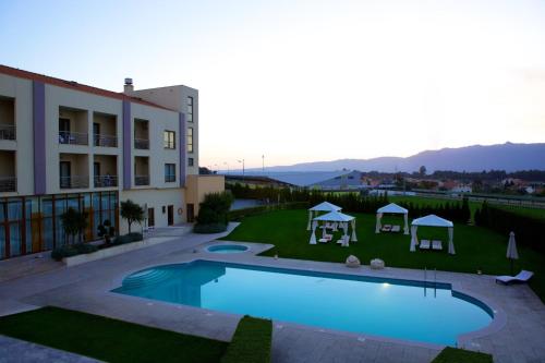a large swimming pool in front of a building at Hotel SJ in Tondela