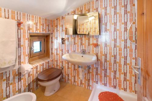 een badkamer met een wastafel, een toilet en een spiegel bij Appartamento Pablo in Livigno
