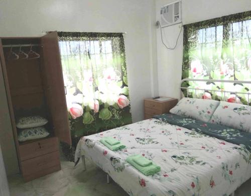 a bedroom with a bed and windows with flowers at DeiHouse in Samal