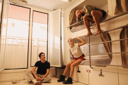 a man and a woman sitting on bunk beds at Onefam Ramblas in Barcelona