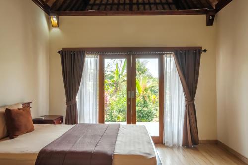 a bedroom with a bed and a large window at TwoSpaces Living at Balian Green Lagoon in Balian