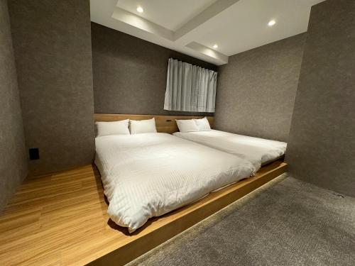 a bedroom with two beds with white sheets and a window at TABISAI HOTEL Lunon Tenjin in Fukuoka