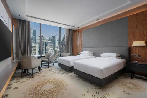 two beds in a hotel room with a view at Hyatt Regency Bangkok Sukhumvit in Bangkok