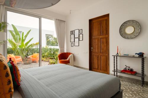 a bedroom with a bed and a large window at La Meira 3BHK Villas in Assagao with Private Pool, Garden, Caretaker, Kitchen & Security in Vagator