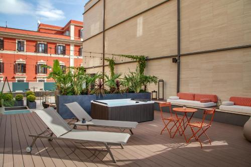 a rooftop patio with chairs and tables on a building at The Spring House Hotel Rome Vatican, Tapestry Collection Hilton in Rome
