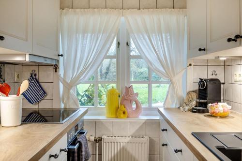 Una cocina con gabinetes blancos y una ventana. en Alkoven, en Braderup