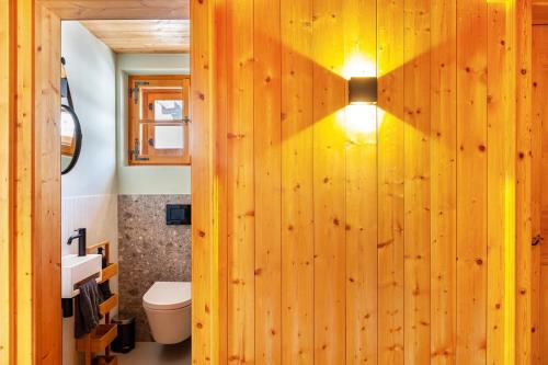 a bathroom with a wooden wall with a light on it at Chalet Flocke Sternschnuppe in Sankt Anton am Arlberg