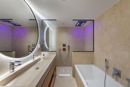une salle de bain avec une baignoire, un lavabo et un miroir dans l'établissement Chalet Carriaz Meribel Village 14pers à 5min à pieds des pistes et commerces, à Les Allues