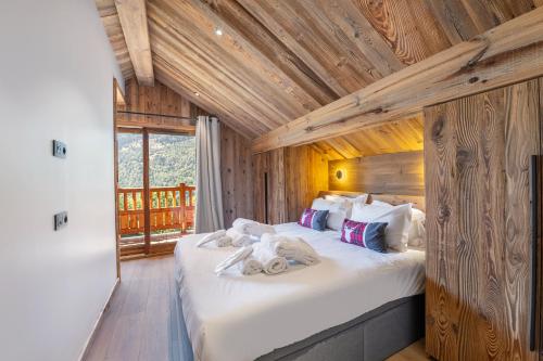 une chambre avec un grand lit dans une pièce aux murs en bois dans l'établissement Chalet Carriaz Meribel Village 14pers à 5min à pieds des pistes et commerces, à Les Allues