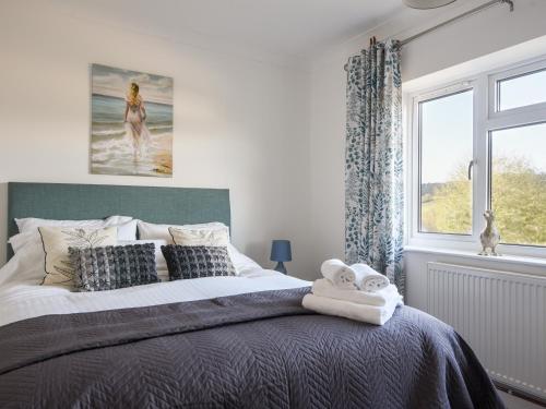 a bedroom with a large bed and a window at Hook Farm Cottage in Lyme Regis