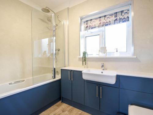 a bathroom with blue cabinets and a sink and a window at Hook Farm Cottage in Lyme Regis