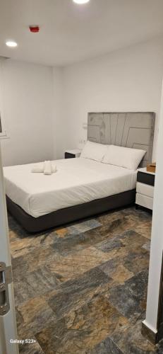 a bedroom with a white bed with a wooden floor at HOSTAL NERVION in Seville