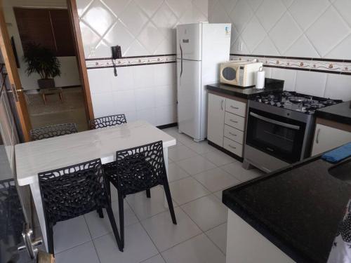 La cuisine est équipée d'une table, de chaises et d'un réfrigérateur. dans l'établissement Apartamento Todos os Santos próximo da Unimontes, à Montes Claros