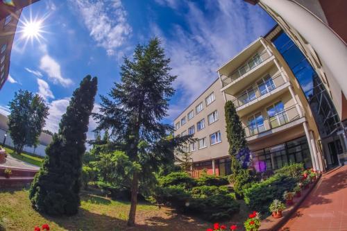 a view of a building with trees and flowers at Hotel Uniwersytecki in Toruń