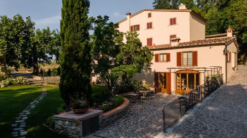 una grande casa bianca con un albero in cortile di Agriturismo Torreghiotta a Pistoia