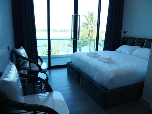 a bedroom with a bed and chairs and a large window at Pool Villa Rimkhong Nakhorn Panom 