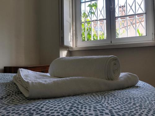 duas toalhas numa cama com uma janela em Casa da Branca Gonta Colaço em Lisboa