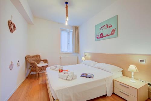 1 dormitorio con 1 cama blanca y 1 silla en Heart Of Riva - 100 Mt. From The Lake - Happy Rentals, en Riva del Garda