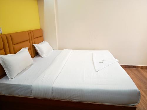 a large bed with white sheets and pillows at STAYMAKER Karanji Paradise - Next to Liquor station in Bangalore